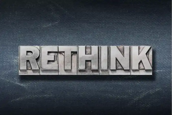 Metal letterpress blocks spelling 'RETHINK' on a denim background.