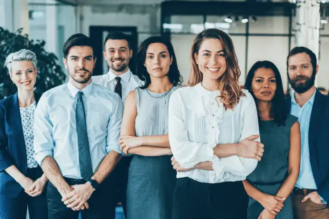 Diverse team of seven professionals in business attire standing together with hands joined in unity