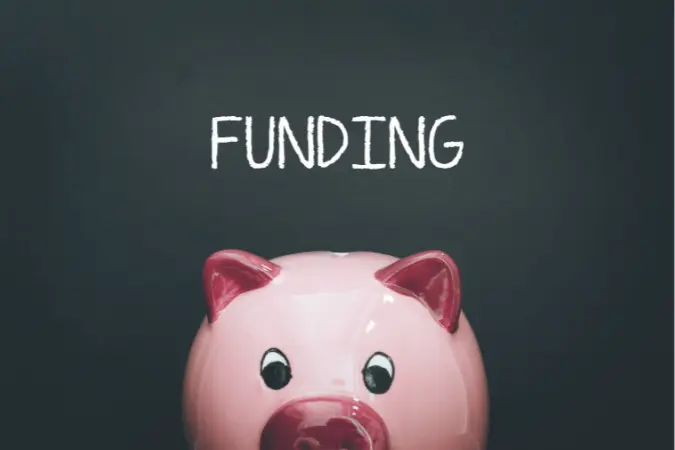 Pink piggy bank with the word 'FUNDING' on a dark gray background