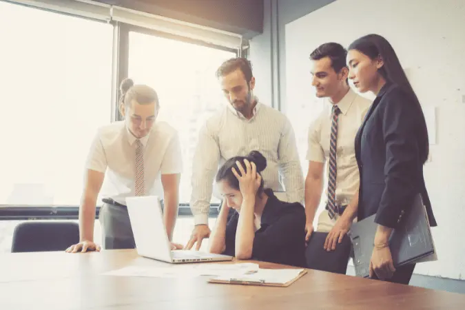 Team of four professionals gathered around a laptop in an intense discussion.