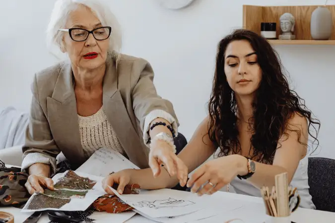 Experienced mentor and younger professional collaborating on work at a desk