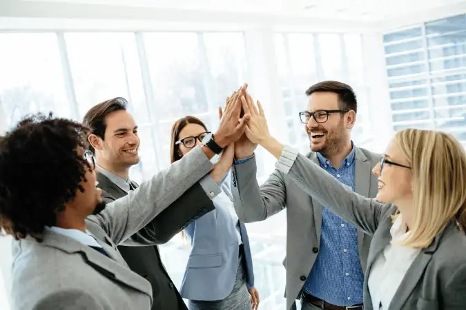 Diverse sales team high-fiving and celebrating success together