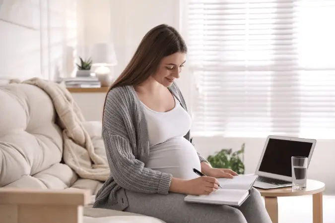 Pregnant female professional working from home planning maternity leave