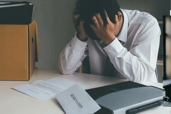 Male professional at desk looking stressed while reviewing redundancy notice