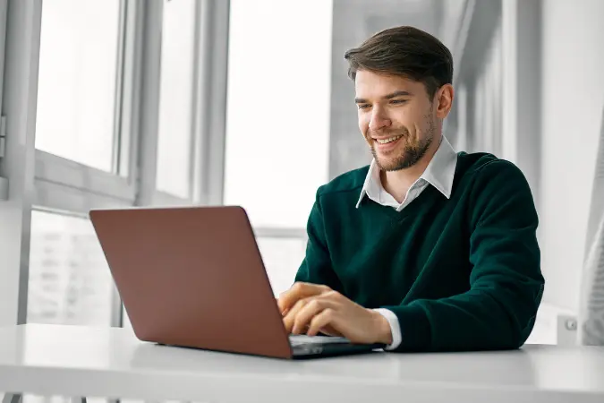 Young professional working at a laptop in a bright modern office.