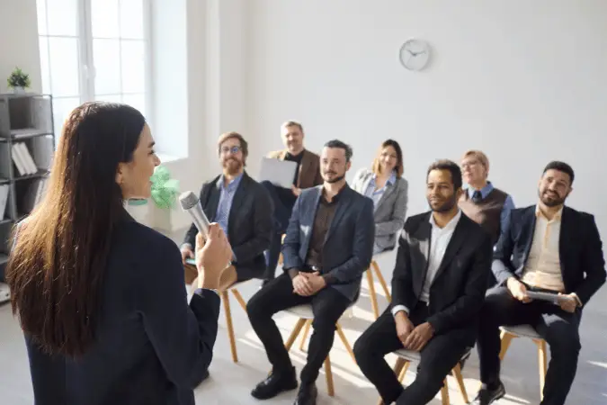 Presenter speaking to a seated group during a team training session.