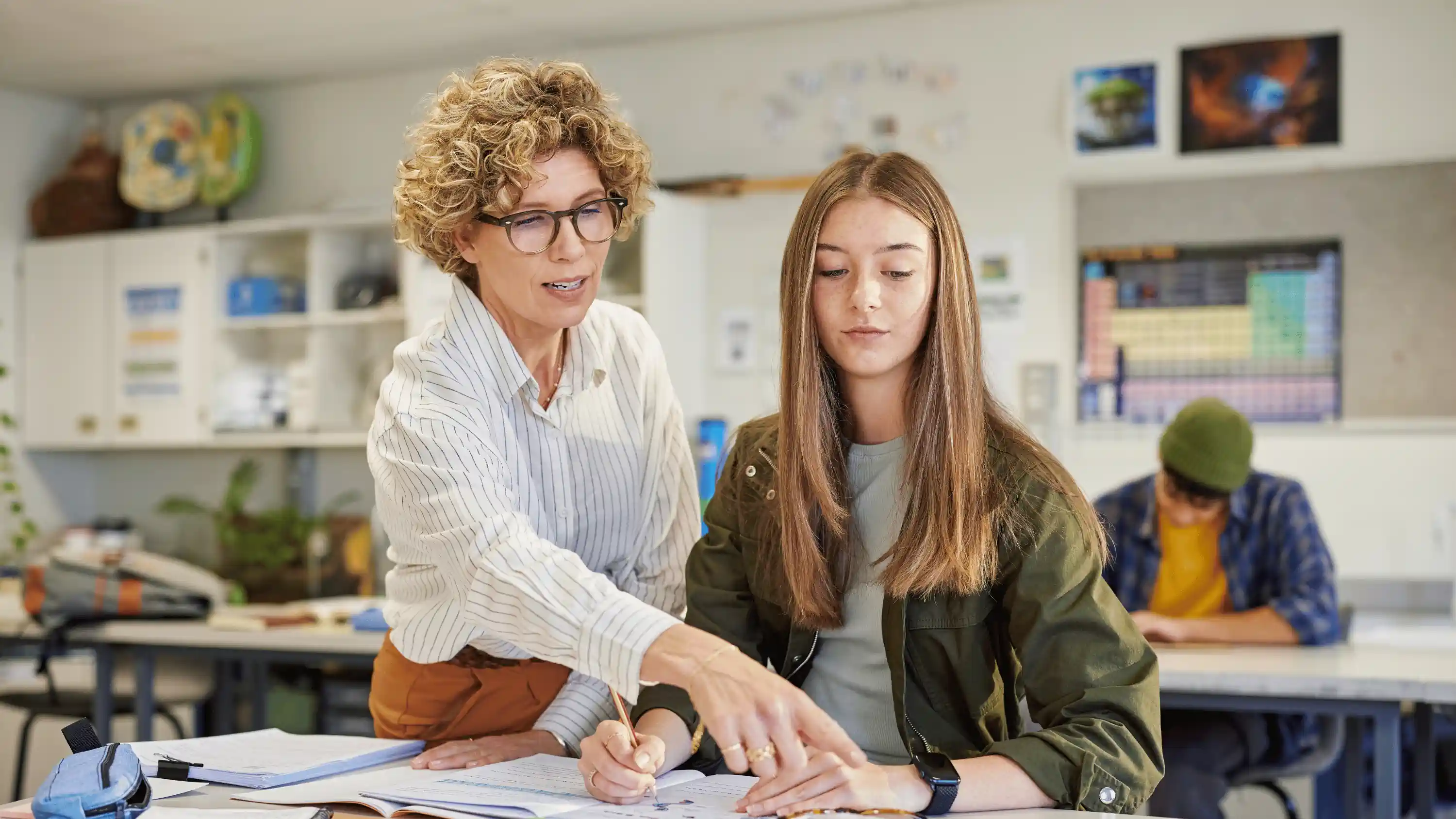 Tutor guiding a student through her coursework in a classroom.